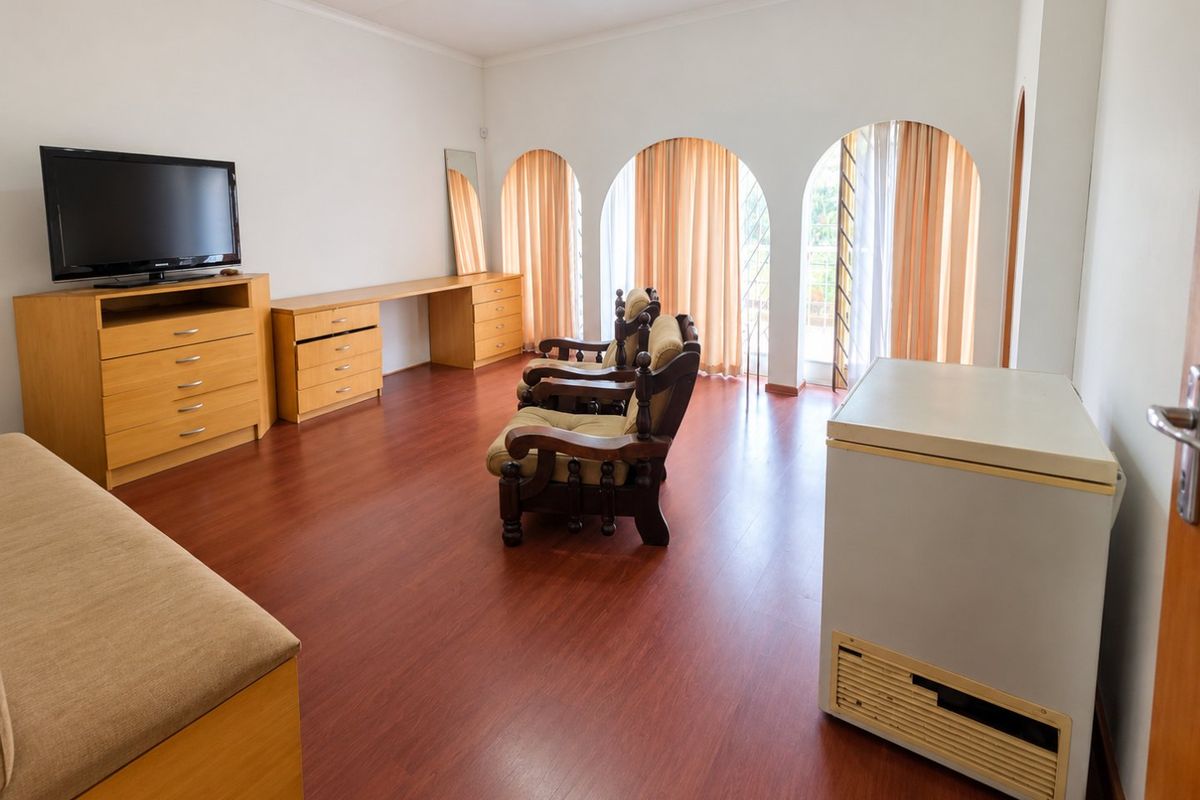 Spacious bedroom featuring laminate flooring, built-in cabinetry, and distinctive arched windows that provide natural light and access to the exterior.