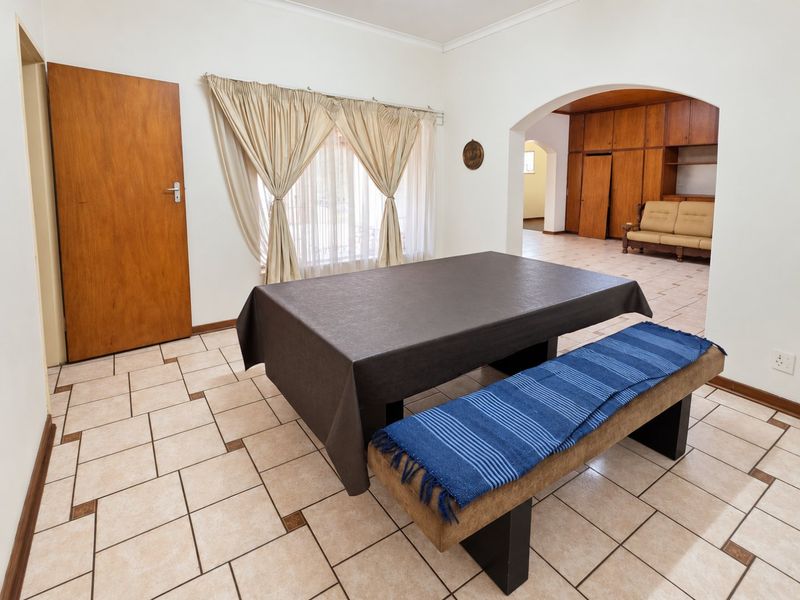 Dining area featuring ceramic tile flooring, a decorative archway leading to an adjacent space, and built-in wooden cabinetry.