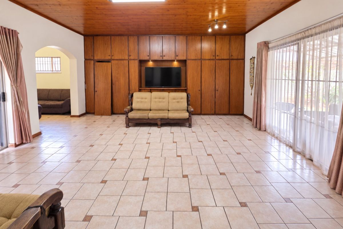 Spacious living room featuring a warm timber ceiling, extensive built-in cabinetry, and large sliding glass doors that provide ample natural light.