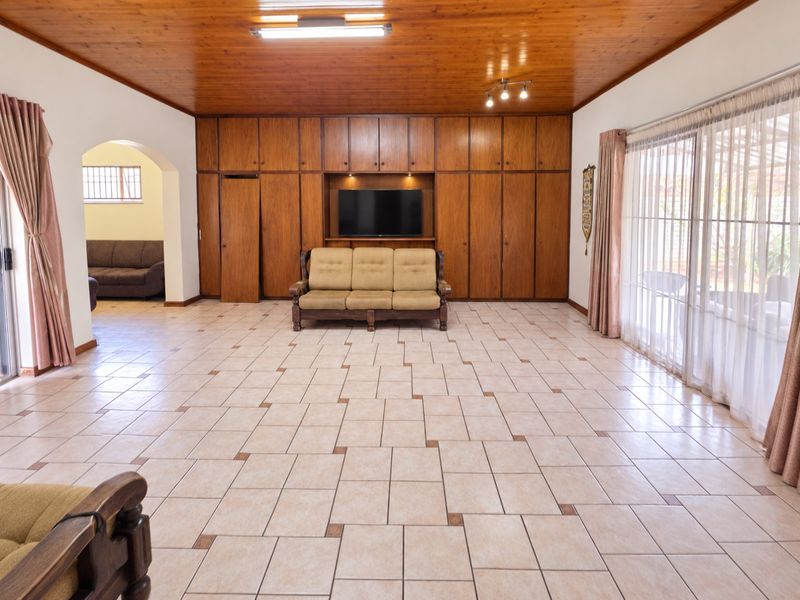 Spacious living room featuring a warm timber ceiling, extensive built-in cabinetry, and large sliding glass doors that provide ample natural light.