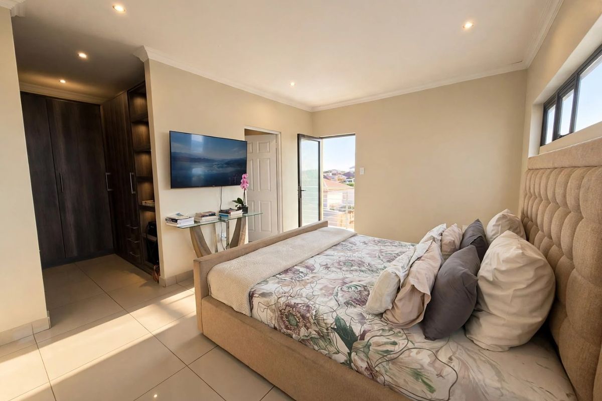 Spacious bedroom featuring tiled flooring, built-in cupboards, recessed downlighting, and direct access to a private balcony.