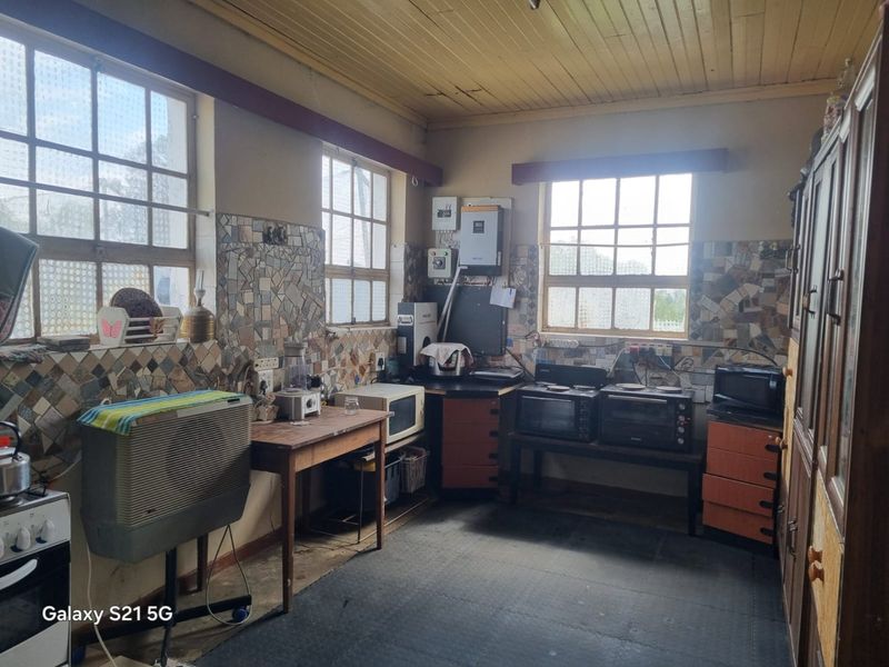 A dated kitchen area featuring a timber ceiling, mosaic-style tiled splashbacks, and integrated electrical infrastructure including an inverter system.