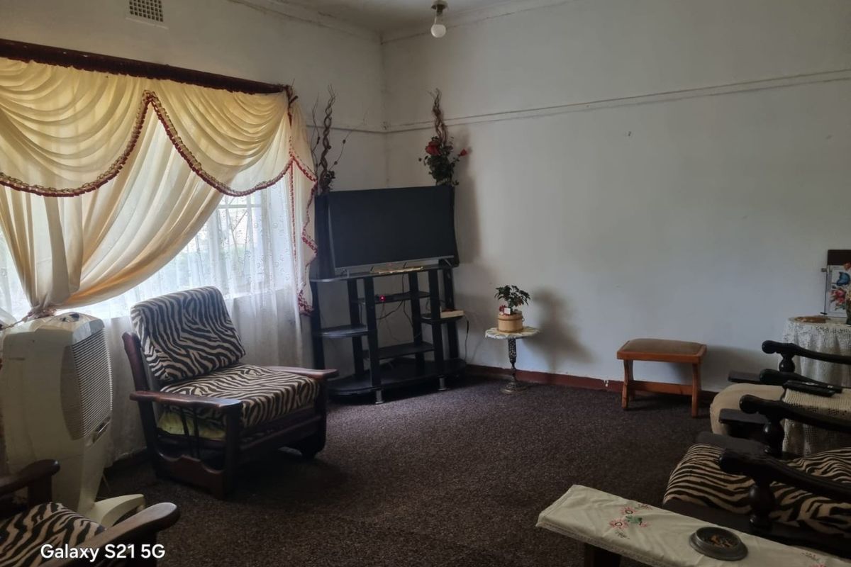 A living room featuring traditional picture rails and a ventilation grille, currently finished with dated carpeting and requiring cosmetic updates.