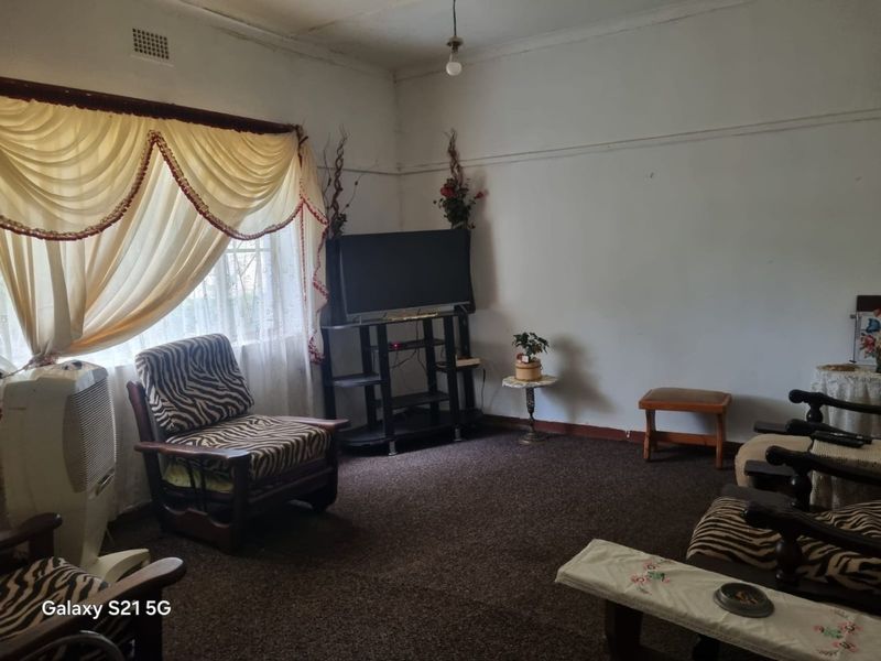 A living room featuring traditional picture rails and a ventilation grille, currently finished with dated carpeting and requiring cosmetic updates.