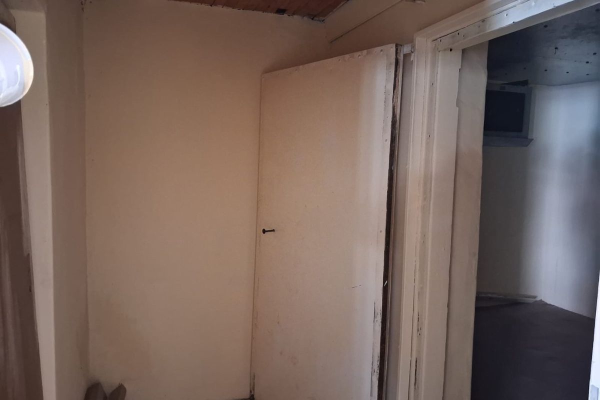 A vacant hallway area featuring timber ceiling paneling and internal doors, requiring cosmetic updates and repairs to finishes.