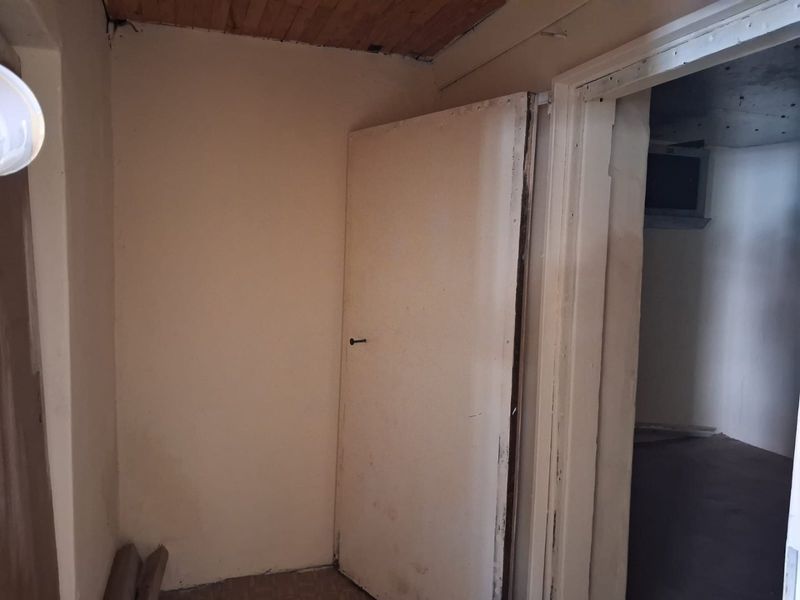 A vacant hallway area featuring timber ceiling paneling and internal doors, requiring cosmetic updates and repairs to finishes.