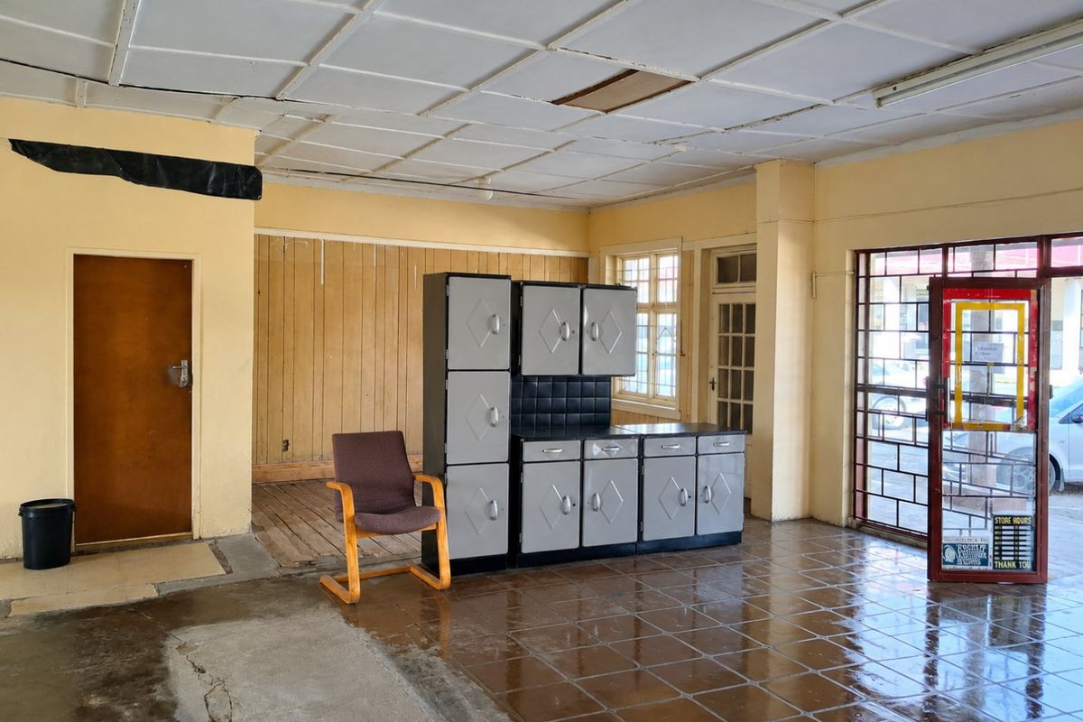 Open plan commercial space featuring tiled flooring, suspended ceiling, and security gate access, currently in need of renovation and repair.