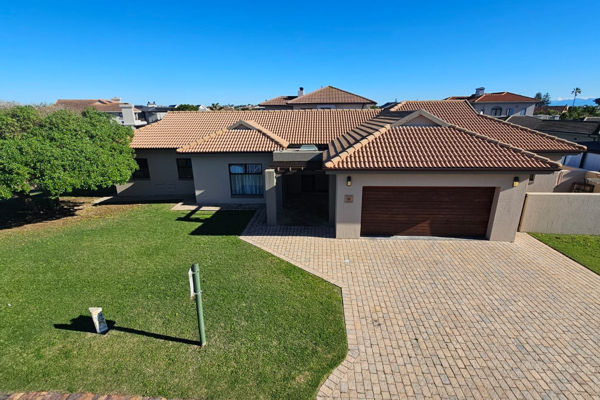 Aerial view of a well-maintained single-story residential property featuring a tiled roof, paved driveway, double garage, and a spacious front lawn.