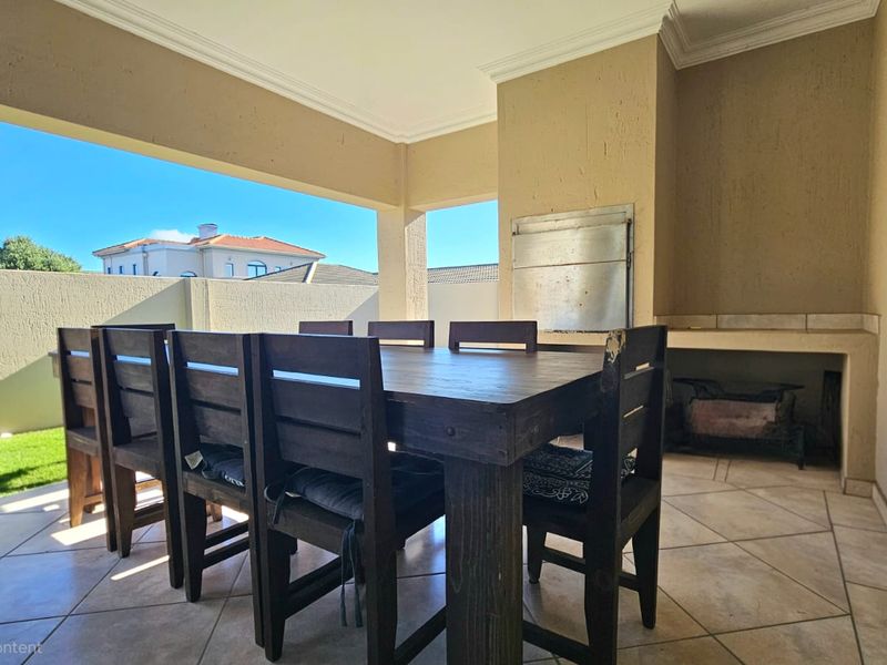 Covered patio area featuring a built-in braai and tiled flooring, providing a functional outdoor entertainment space.