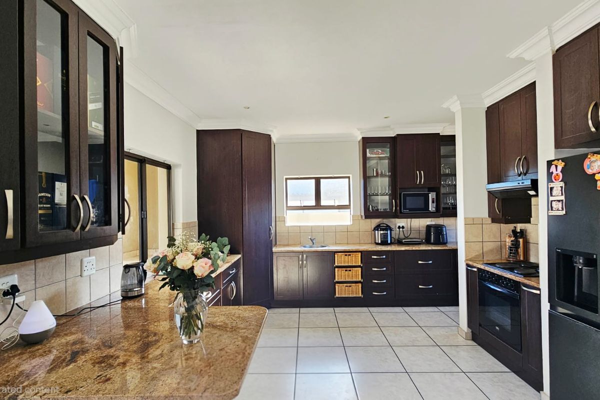 Spacious kitchen featuring dark wood cabinetry, granite countertops, tiled flooring, and integrated appliances, offering a functional and well-maintained cooking space.