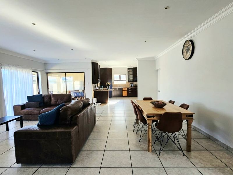 Spacious open-plan living and dining area featuring tiled floors, recessed lighting, and seamless flow to the kitchen and outdoor patio space.