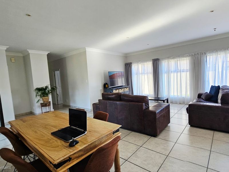 Spacious open-plan living and dining area featuring neutral tiled flooring, recessed lighting, and large sliding glass doors providing ample natural light.