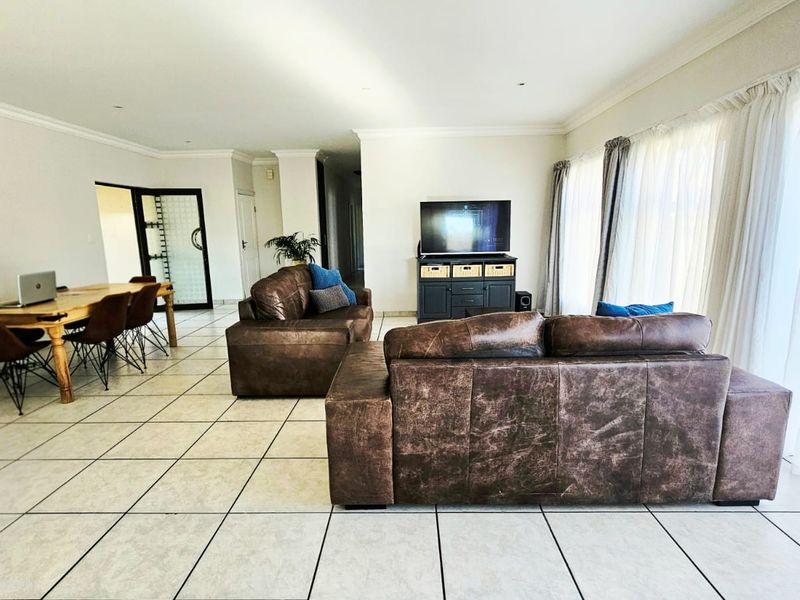 Spacious open-plan living and dining area featuring neutral tiled flooring, recessed lighting, and large sliding glass doors providing ample natural light.