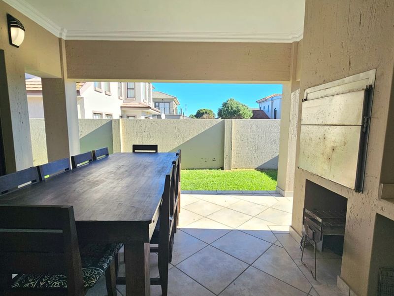 Covered patio area featuring a built-in braai, tiled flooring, and direct access to a private rear garden space.