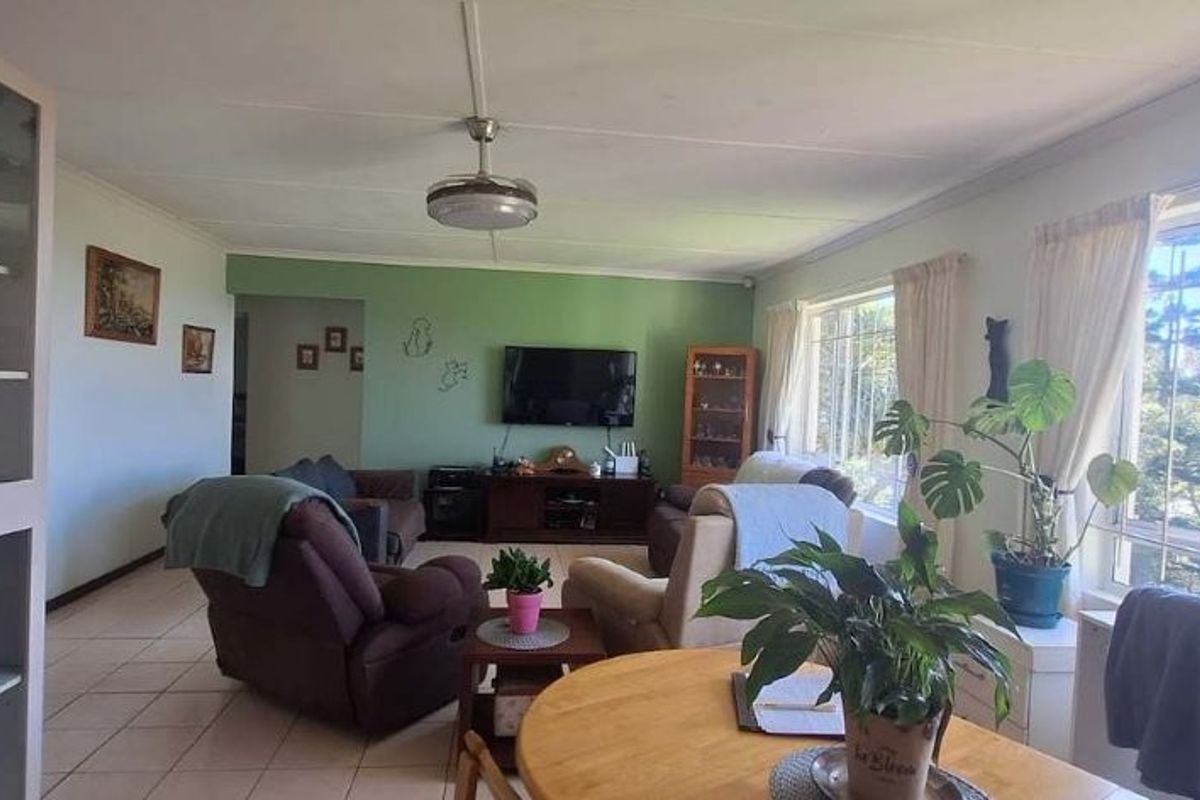 Spacious living room featuring tiled flooring, a ceiling fan, and large windows with security bars, offering a bright and functional living space.