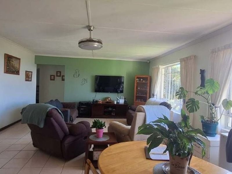 Spacious living room featuring tiled flooring, a ceiling fan, and large windows with security bars, offering a bright and functional living space.