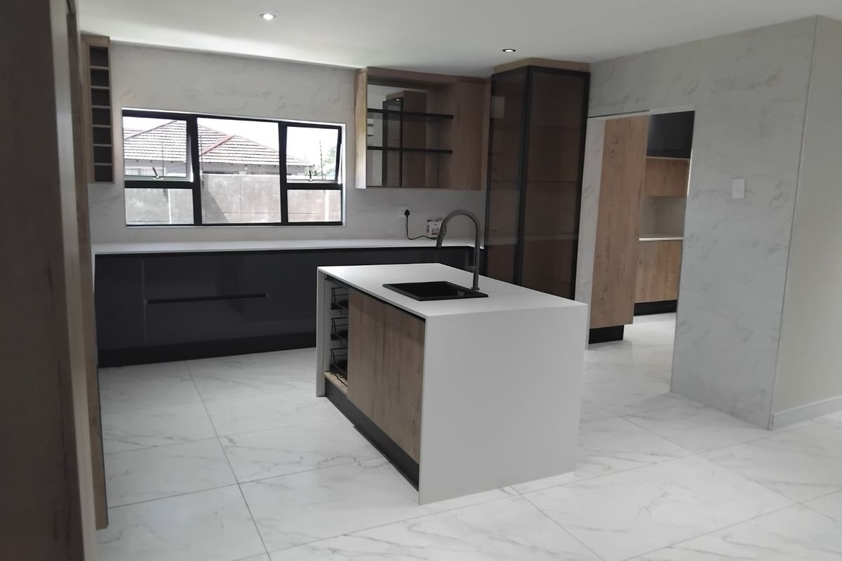 Modern, newly renovated kitchen featuring a central island with quartz countertops, sleek cabinetry, and large-format marble-look floor tiles.