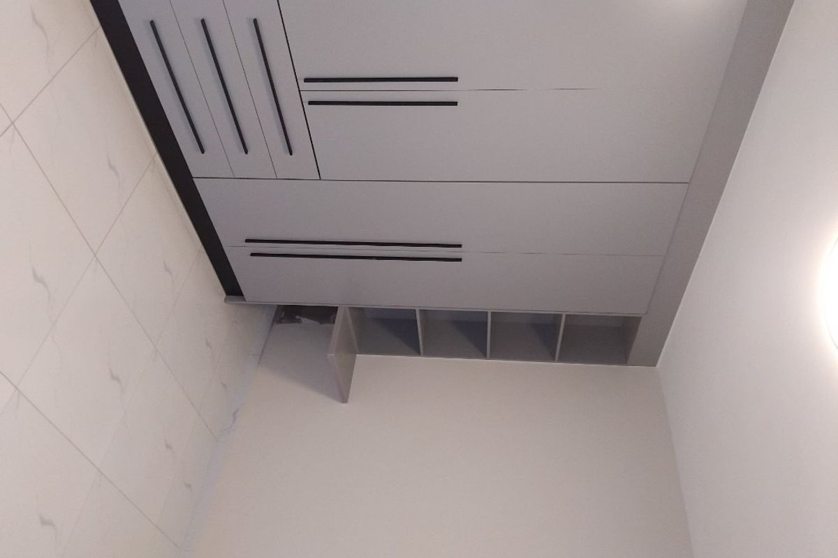 A bedroom featuring modern grey built-in wardrobes with integrated shelving and tiled flooring.