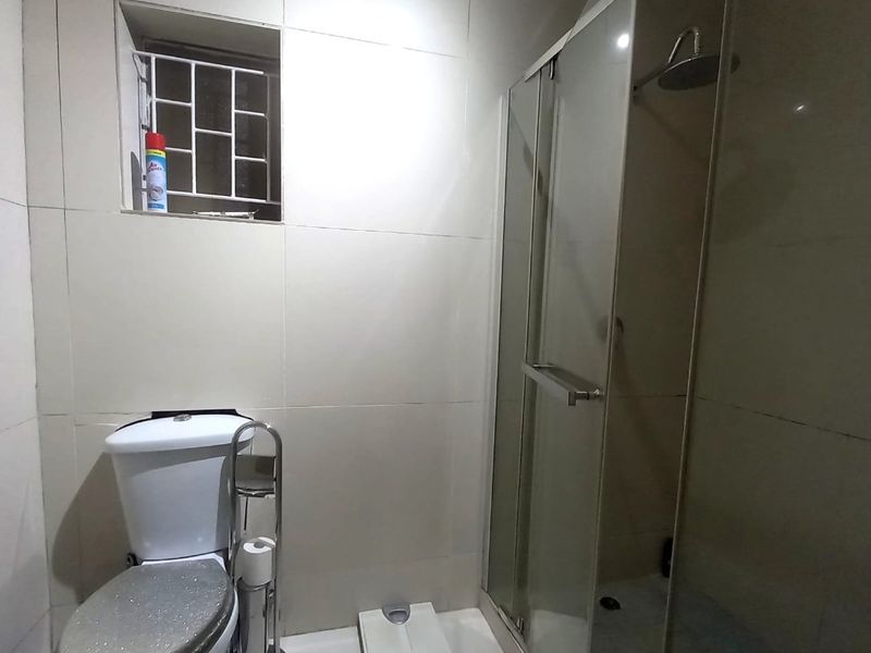 A functional bathroom featuring tiled walls and flooring, a glass shower enclosure, and a standard toilet.