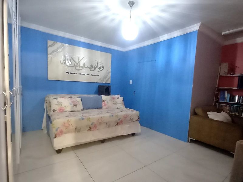 A bedroom featuring tiled flooring, built-in cupboards, and decorative coving, finished with bright blue accent walls.