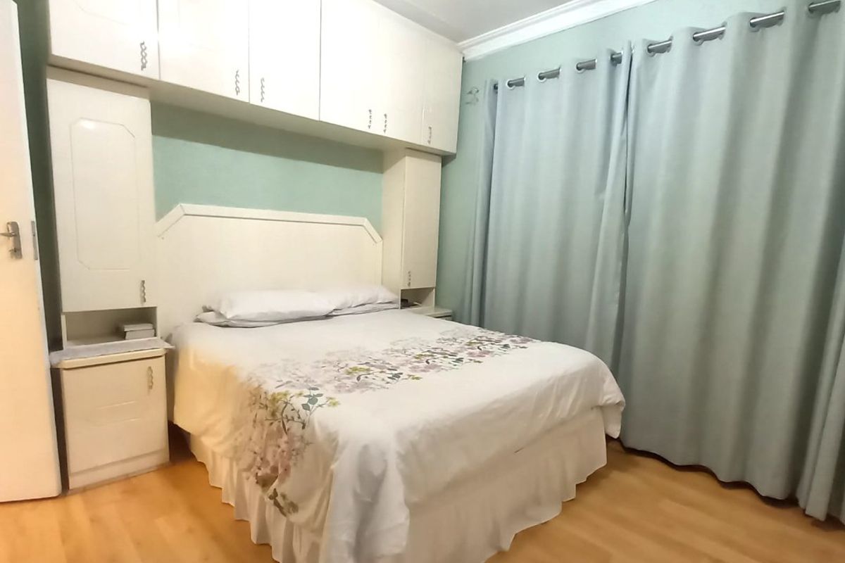 A bedroom featuring laminate flooring, built-in cupboards with overhead storage, and a built-in headboard.