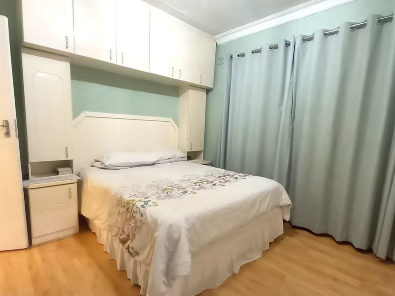 A bedroom featuring laminate flooring, built-in cupboards with overhead storage, and a built-in headboard.