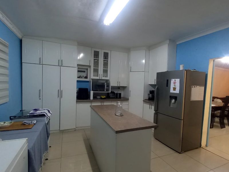 A functional kitchen featuring white built-in cabinetry, a central island with laminate countertops, and tiled flooring.