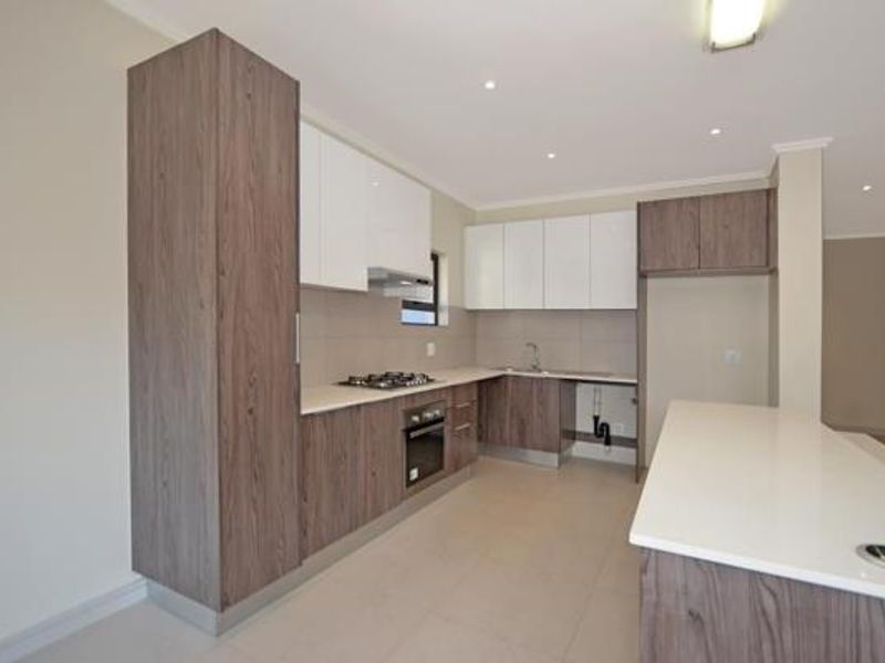 Modern kitchen featuring two-tone cabinetry, stone countertops, a central island, and integrated appliances including a gas hob and oven.