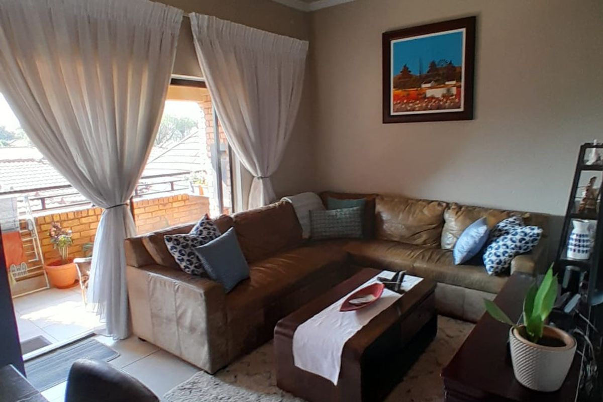 A comfortable living room featuring tiled flooring and a sliding glass door providing access to an outdoor balcony area.