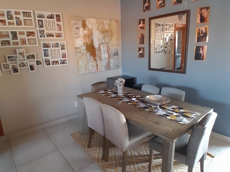 A well-maintained dining room featuring neutral tiled flooring and decorative crown molding, providing a functional space for family meals.