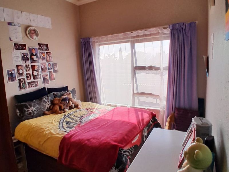 A functional bedroom featuring a large sliding window, coved ceiling details, and neutral wall finishes, providing a comfortable living space.