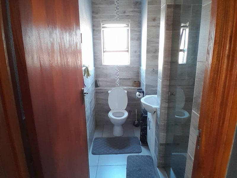 A functional bathroom featuring tiled walls, a vanity basin, a toilet, and a glass-enclosed shower area.