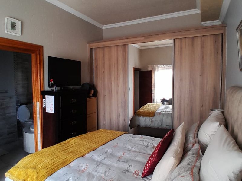 A well-maintained bedroom featuring a large built-in wardrobe with mirrored sliding doors and direct access to an en-suite bathroom.