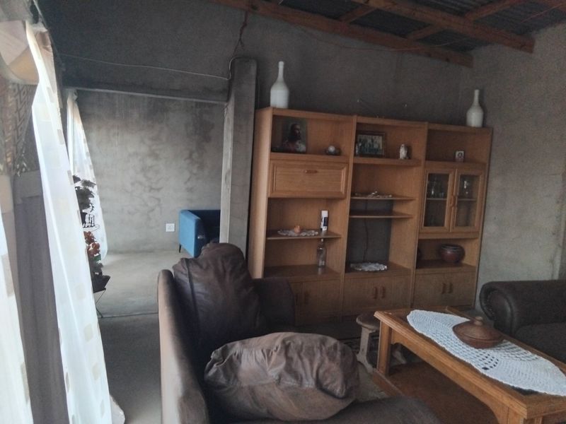 Living area featuring raw, unfinished concrete walls and exposed timber roof beams, offering a rustic, industrial-style foundation ready for renovation.
