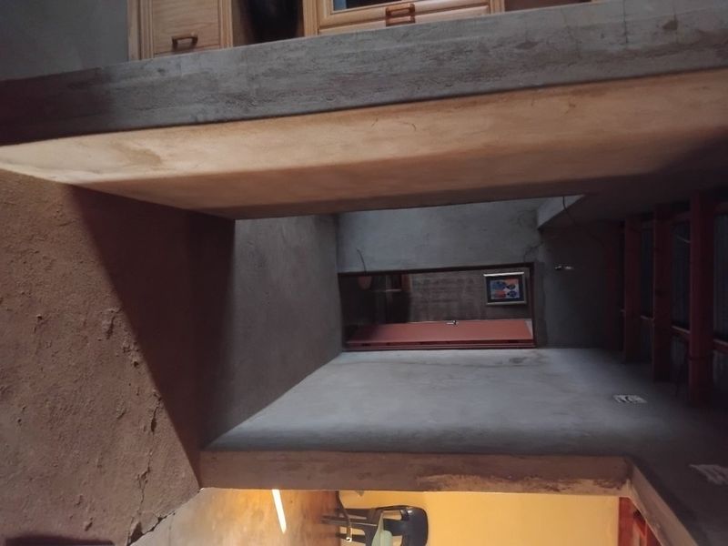 An unfinished interior hallway space featuring raw concrete walls and ceilings, requiring further construction or finishing work to complete the interior aesthetic.