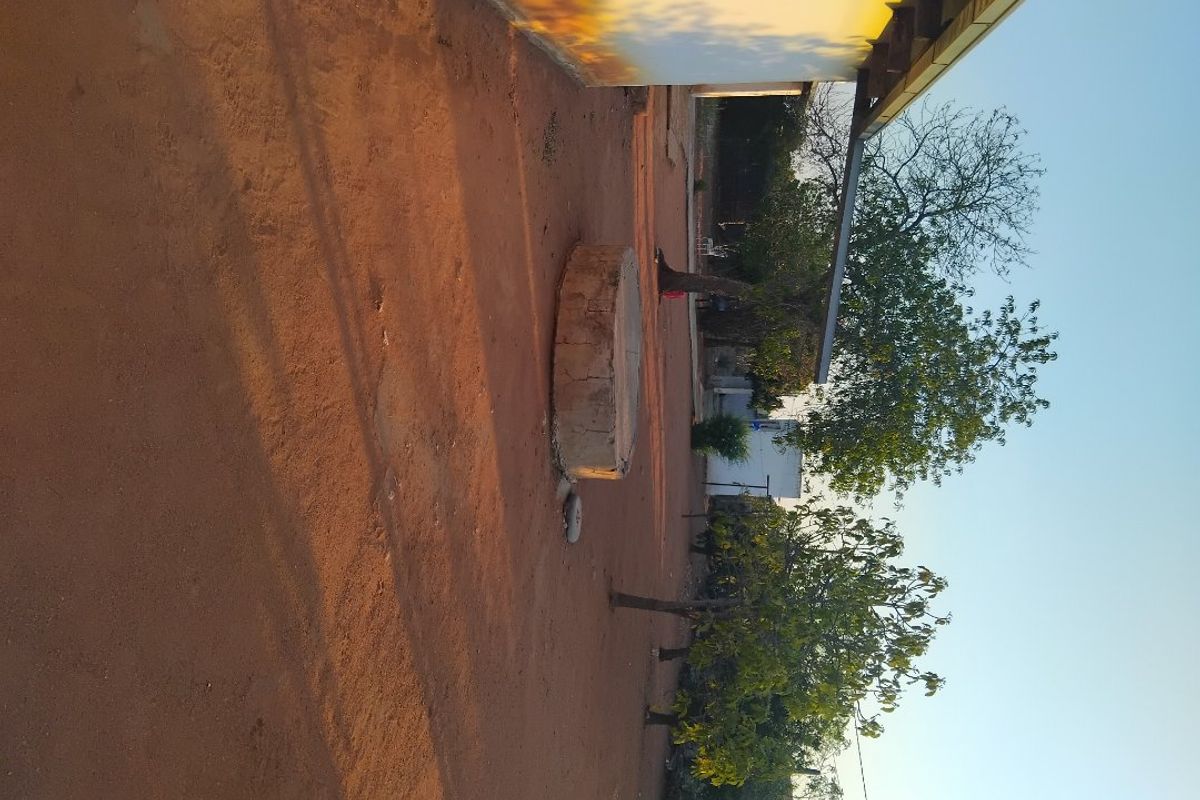 A view of the rear exterior area featuring a concrete well structure and unpaved ground surface.