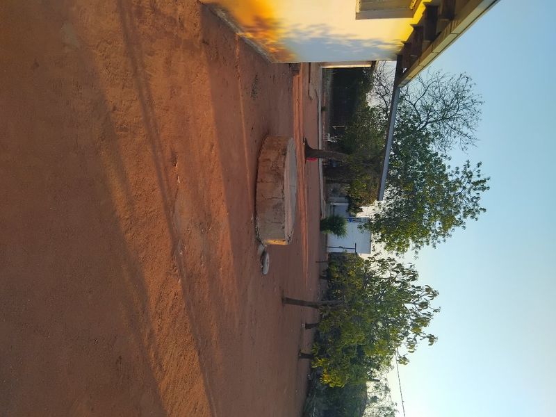 A view of the rear exterior area featuring a concrete well structure and unpaved ground surface.