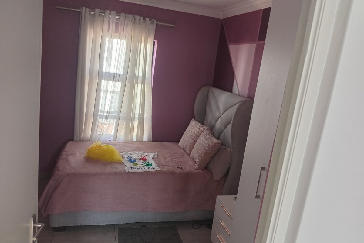 A compact bedroom featuring tiled flooring, a built-in cupboard, and purple accent walls, offering a functional space for rest.