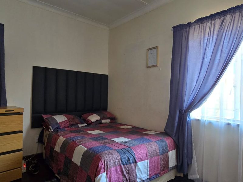 A standard bedroom featuring neutral walls, cornice detailing, and windows fitted with security bars.
