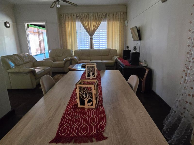 Open plan living and dining area featuring laminate flooring, a ceiling fan, and neutral wall finishes with classic picture rails.