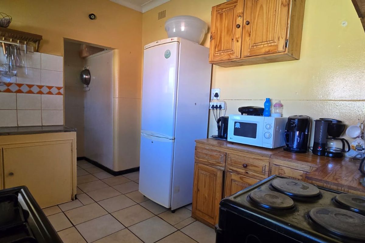 A functional kitchen featuring wooden cabinetry, tiled backsplash, and tiled flooring, offering a dated aesthetic with potential for modernization.