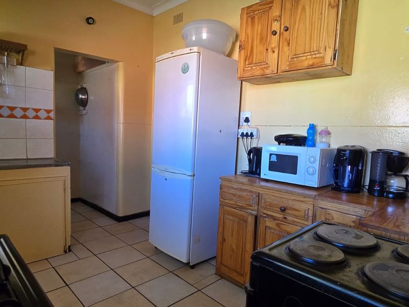 A functional kitchen featuring wooden cabinetry, tiled backsplash, and tiled flooring, offering a dated aesthetic with potential for modernization.