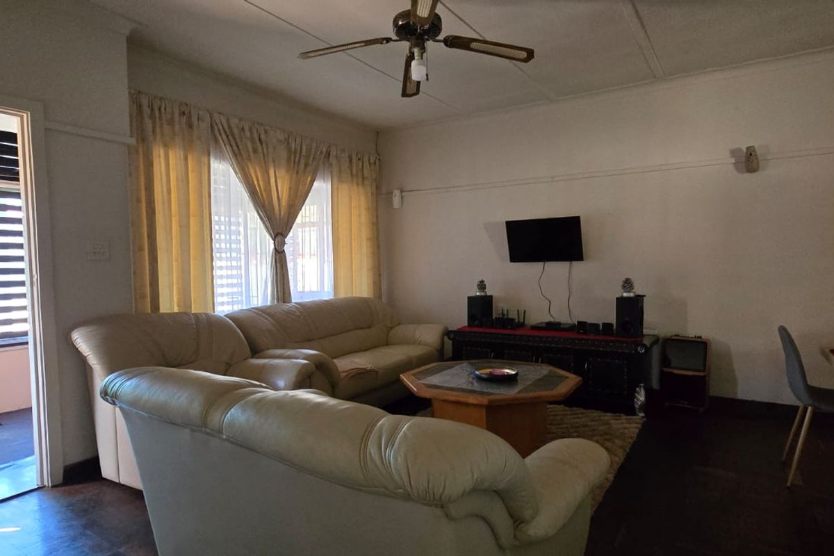 A spacious living room featuring timber flooring, a ceiling fan, and a classic picture rail, offering a comfortable and functional layout.