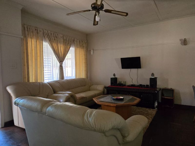 A spacious living room featuring timber flooring, a ceiling fan, and a classic picture rail, offering a comfortable and functional layout.