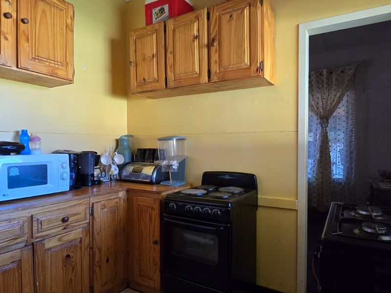 A compact kitchen featuring traditional wooden cabinetry and a freestanding stove, offering a functional layout with potential for modern updates.