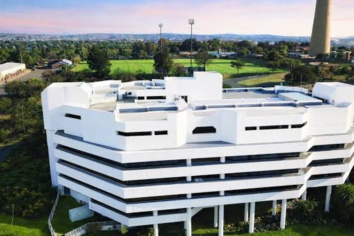 Aerial view of a multi-story commercial office building featuring a modern white facade and surrounding landscaped grounds.