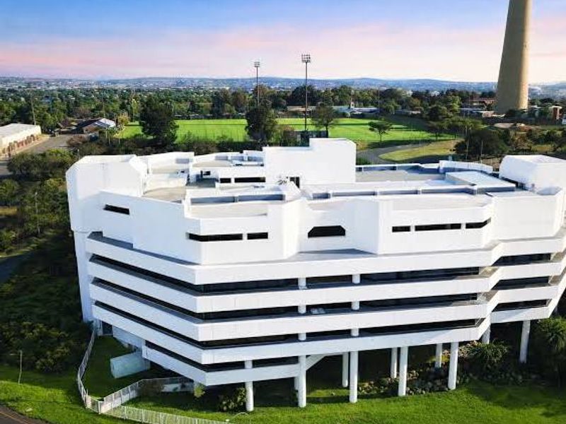 Aerial view of a multi-story commercial office building featuring a modern white facade and surrounding landscaped grounds.