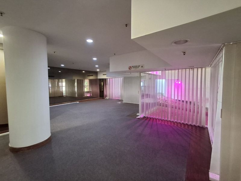 Spacious commercial gym area featuring mirrored walls, recessed lighting, and vertical blinds, offering a versatile open-plan layout suitable for various fitness activities.