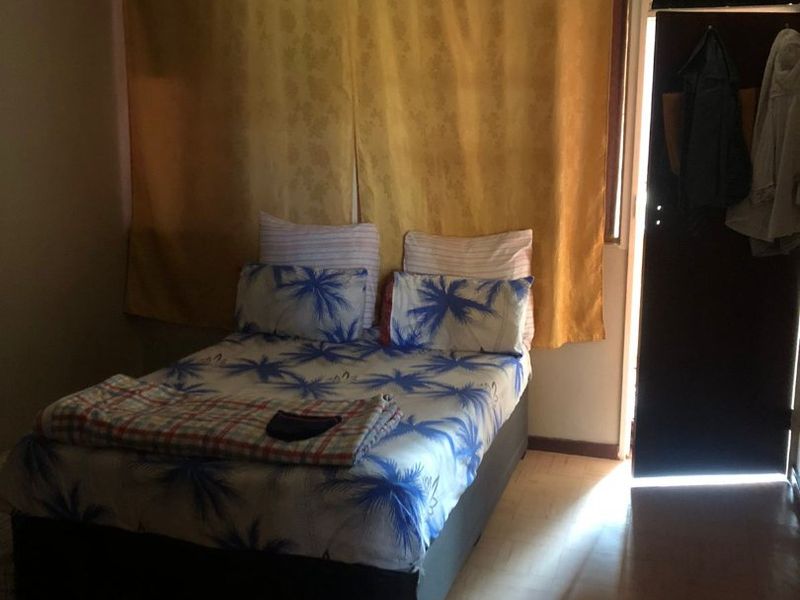 A bedroom featuring laminate flooring and natural light entering through a doorway, providing a functional space for rest.