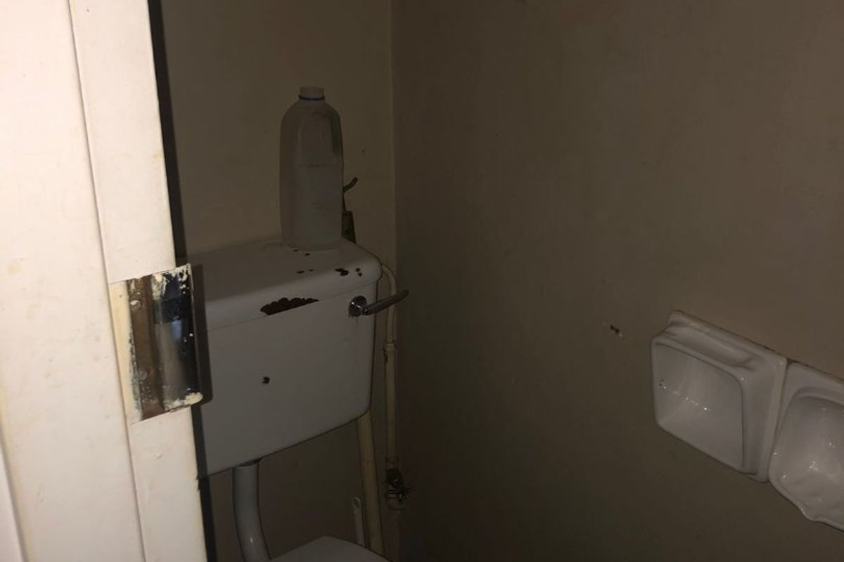 A small, dated bathroom featuring a standard toilet and wall-mounted soap holders, requiring cosmetic updates and maintenance.